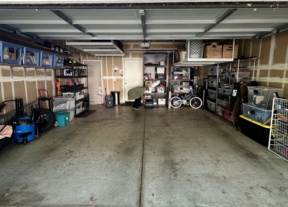 After: the same garage with a clear floor and labeled bins on shelves