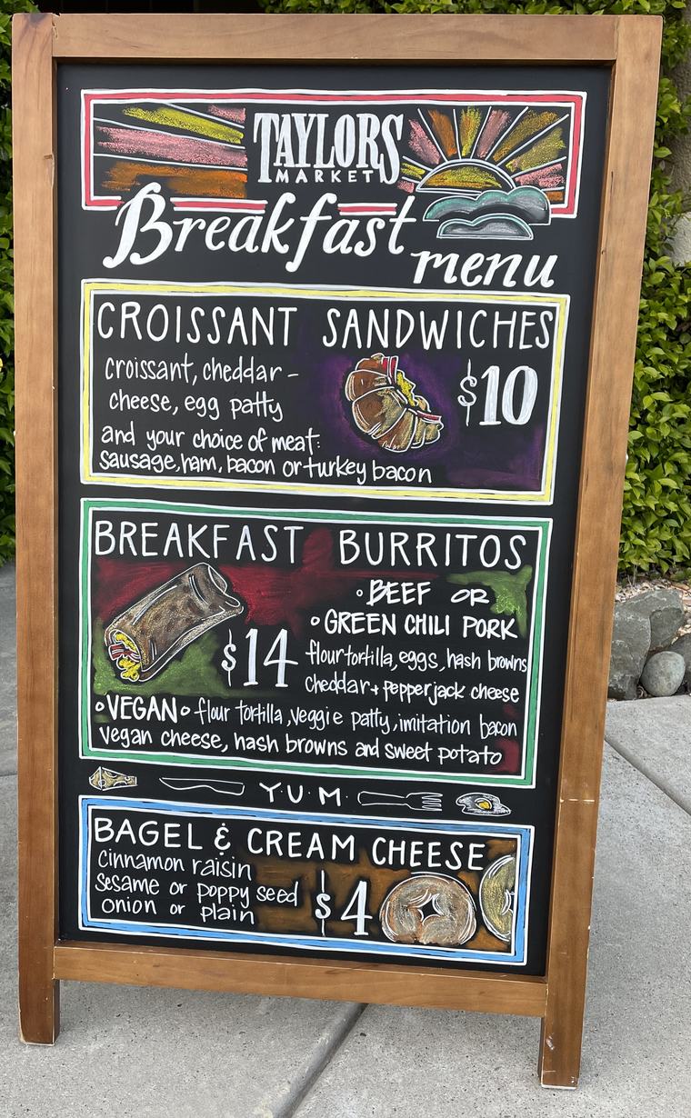 Hand-painted chalkboard breakfast menu with illustrated croissant sandwich, burrito and bagel