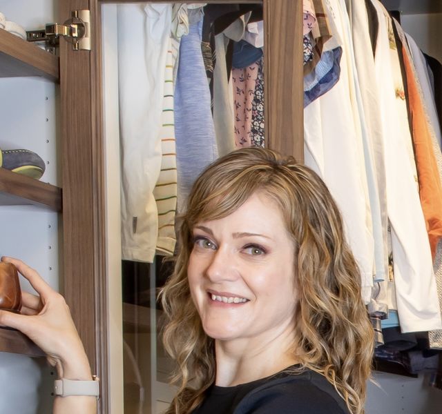 Kelli smiling while arranging shoes in an organized walk-in closet