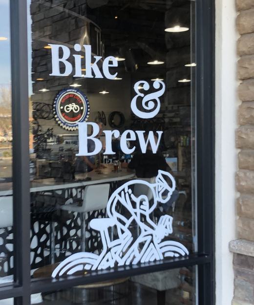Painted window reading Bike and Brew with a line illustration of a cyclist