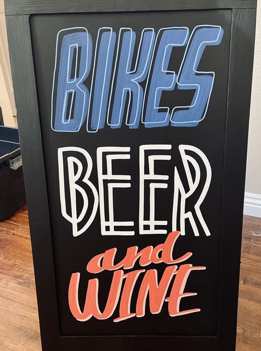 Sidewalk chalkboard lettered Bikes, Beer and Wine