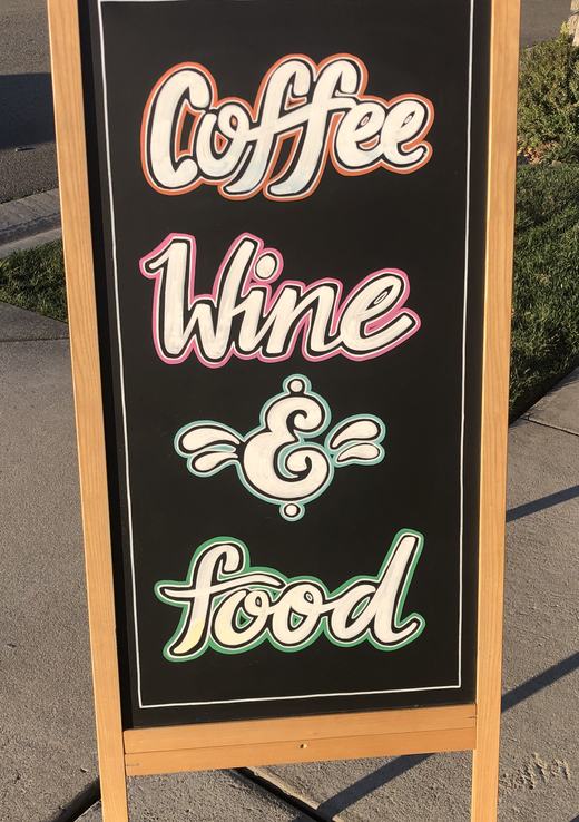 Sidewalk chalkboard sign lettered Coffee, Wine and food